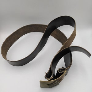 May include: A brown leather belt with a brass buckle featuring a five-pointed star. The buckle has a raised design of a hammer and sickle.
