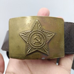 May include: A gold-toned belt buckle with a star and hammer and sickle design.
