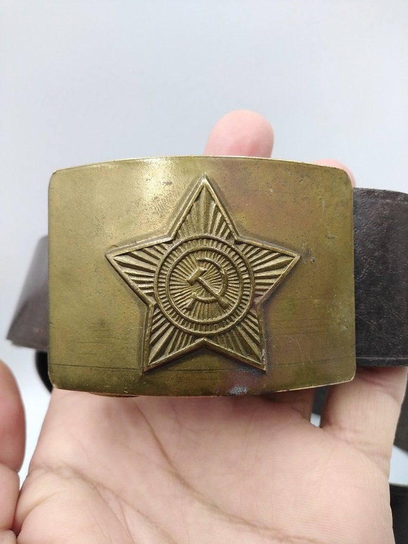 May include: A gold-toned belt buckle with a star and hammer and sickle design.