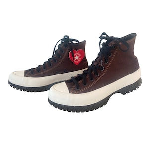 May include: A pair of brown high-top Converse sneakers with a white rubber sole and a red heart with a white star logo on the side.