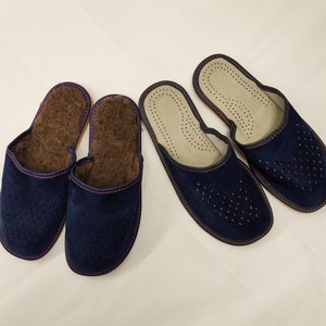 Puede incluir: Dos pares de zapatillas de ante azul marino. Un par es cerrado con forro marr&oacute;n y costuras rosas. El otro par es abierto con un dise&ntilde;o perforado y una plantilla de color claro. Ambos pares est&aacute;n sobre una superficie blanca.