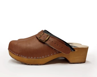 May include: Brown leather clog with a buckle strap and a wooden sole.