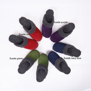 Op de afbeelding: Acht paar suède pantoffels in verschillende kleuren, waaronder rood, groen, paars en donkerblauw. Elke pantoffel heeft een grijze fleece voering.