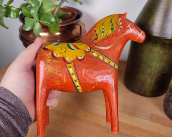 May include: A hand-painted wooden Dala horse, a traditional Swedish folk art toy. The horse is painted in bright red, yellow, and green colors with intricate details.