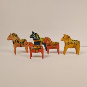 May include: Five hand-painted wooden horses, known as Dala horses, in various colours and designs. The horses are traditional Swedish folk art.