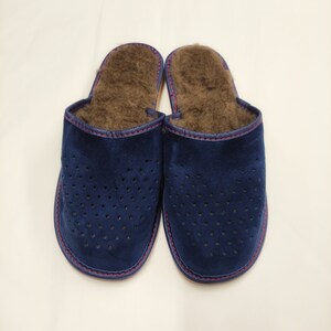 Puede incluir: Un par de zapatillas de ante azul marino con un dise&ntilde;o perforado. El interior est&aacute; forrado con piel marr&oacute;n y los bordes est&aacute;n ribeteados con costuras rojas. Estas zapatillas est&aacute;n dise&ntilde;adas para uso en interiores.