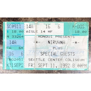 May include: A rectangular concert ticket for a Nirvana performance at the Seattle Center Coliseum on Friday, September 11, 1992, at 8:00 PM. The ticket features a light blue and white color scheme with printed details including section 14A, row 16, seat 6.