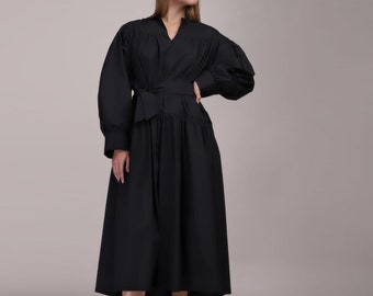May include: A black midi dress with a cinched waist and long sleeves. The dress has a v-neckline and a gathered skirt.