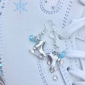 以下が含まれることがあります： 青いクリスタルチャームと銀のスケートチャームが付いた銀のイヤリングのペア