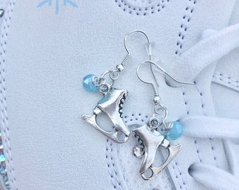 Peut inclure: Une paire de boucles d'oreilles en argent avec un charme en cristal bleu et un charme en patins à glace argentés.