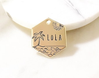 May include: Gold hexagonal pet tag with a palm tree, waves, and sun design. The name "LOLA" is engraved on the tag.
