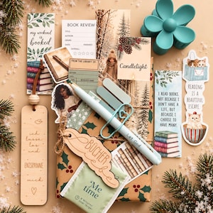 Könnte beinhalten: Ein Set mit Lesezubehör, darunter Lesezeichen mit Texten wie 'my weekend is booked', eine Buchbewertungskarte, ein 'Me time'-Teebeutel, ein hellblauer Stift und eine blaugüne, blumenförmige Haarspange sowie ein Holzlesezeichen mit 'ich lasse los'.
