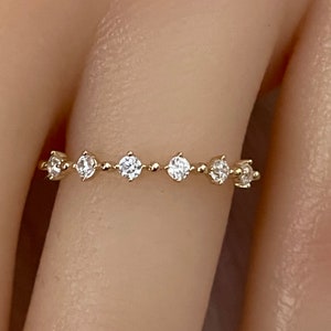 May include: A delicate gold band ring with a row of small, clear gemstones.