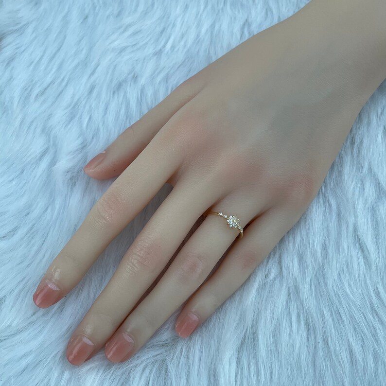 May include: A delicate gold ring with a cluster of small diamonds set in a flower shape.