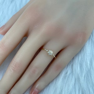 May include: A delicate gold ring with a cluster of small diamonds in the center and a line of smaller diamonds extending from the center.