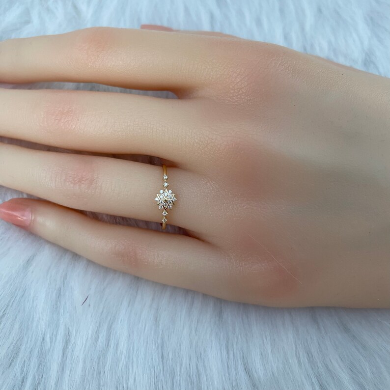 May include: A delicate gold ring with a small, sparkling diamond snowflake design.