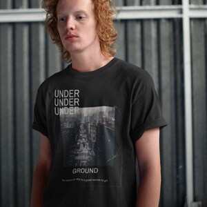 May include: Black t-shirt with the words "UNDER UNDER UNDER" stacked vertically above a cityscape image and the word "GROUND" below. The shirt also has the text "No reason to stay is a good reason to go."