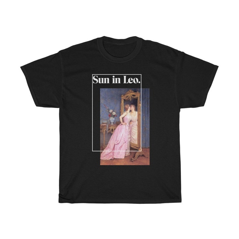 Puede incluir: Camiseta negra con una imagen enmarcada de una pintura que representa a dos mujeres, una con un vestido rosa. El texto "Sun in Leo." est&aacute; en un rect&aacute;ngulo blanco encima de la pintura. La camiseta est&aacute; hecha de un material suave y c&oacute;modo.