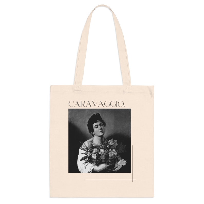 May include: A tote bag with a black and white image of a man holding a basket of fruit. The text "CARAVAGGIO." is printed on the bag.
