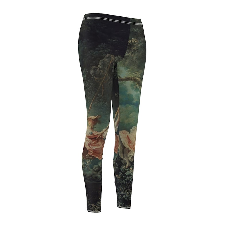 Puede incluir: Leggings con una impresi&oacute;n de una pintura cl&aacute;sica que representa a una mujer en un columpio en un bosque. La obra de arte utiliza tonos verdes, rosas y blancos, sobre un fondo oscuro. Los leggings tienen una cintura alta con una raya blanca.