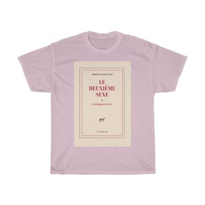 Op de afbeelding: Een lichtroze T-shirt met de boekomslag van "Le Deuxi&egrave;me Sexe" van Simone de Beauvoir. De boekomslag is omlijst met rode en zwarte lijnen en de titel is rood. Dit T-shirt is een casual kledingstuk.