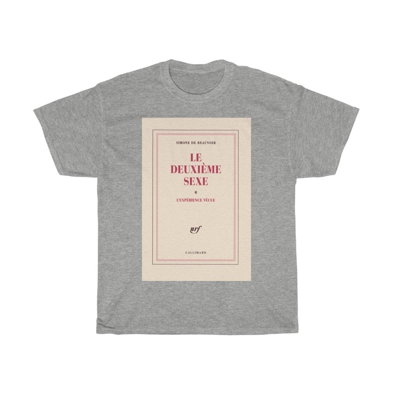 Op de afbeelding: Een lichtgrijs t-shirt met een boekcover-ontwerp. Het ontwerp toont de titel "LE DEUXI&Egrave;ME SEXE" in het rood, met de naam van de auteur en het logo van de uitgever. Het t-shirt is gemaakt van een zacht, comfortabel materiaal.