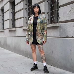 May include: A blazer featuring a multi-coloured, detailed illustrative print in shades of green, tan, and blue, worn over a solid black mini dress. The outfit is paired with white crew socks and black leather lace-up ankle boots with thick soles.