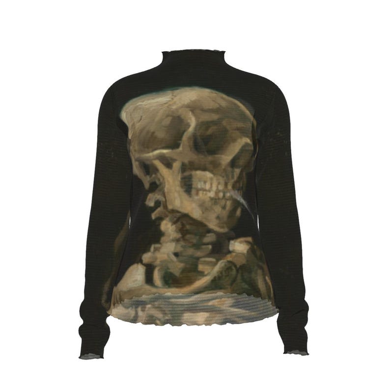 Puede incluir: Camiseta negra de manga larga con una representaci&oacute;n art&iacute;stica detallada de un cr&aacute;neo humano. El cr&aacute;neo est&aacute; representado en tonos marrones y beige, con un aspecto texturizado y pintado. La camiseta tiene un cuello alto y pu&ntilde;os con volantes.