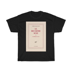 Op de afbeelding: Zwart T-shirt met de boekomslag van "Le Deuxi&egrave;me Sexe" van Simone de Beauvoir. Het ontwerp toont de titel in het rood, de naam van de auteur en het logo van de uitgever.