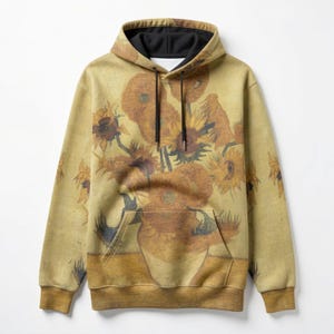Op de afbeelding: Een hoodie met een print van Van Goghs "Zonnebloemen" schilderij. De hoodie heeft een zwarte voering en trekkoorden, met een kangoeroezak. Het kunstwerk is in tinten geel, bruin en zwart, met een vintage esthetiek.