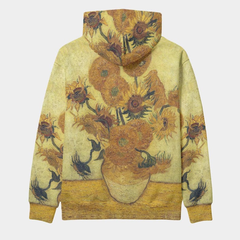 Op de afbeelding: Een gele hoodie met een print van Vincent van Goghs schilderij "Zonnebloemen". Het ontwerp bedekt de hele hoodie, inclusief de capuchon, mouwen en rug, met een gedetailleerde weergave van zonnebloemen in een vaas. Het kleurenpalet omvat geel, oranje en bruin.