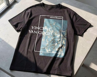 May include: Black t-shirt featuring a rectangular graphic of Vincent Van Gogh's "Almond Blossom" painting. The artwork is set against a light blue background with white text that reads "Vincent Van Gogh" and "Almond Blossom".