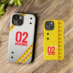 May include: Two phone cases with a yellow and white geometric design. The cases feature the number "02" and the text "Kagamine Rin".