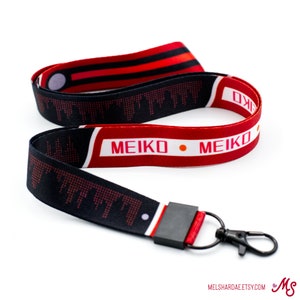 May include: Black and red lanyard with a white background and the text "MEIKO MEIKO" printed on it. The lanyard has a black and white cityscape pattern and a black clip.
