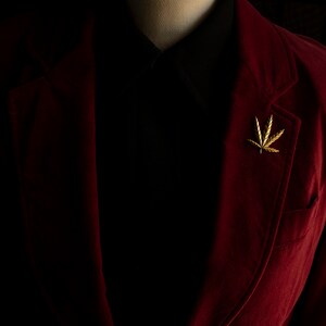 Pode incluir: Um blazer de veludo vermelho com um broche de folha de ouro na lapela.
