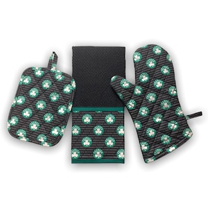 May include: A set of three kitchen accessories featuring the Boston Celtics logo. The set includes a black oven mitt, a black pot holder, and a black kitchen towel with a green border. The accessories are all decorated with a repeating pattern of the Celtics logo.
