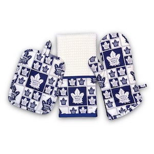 May include: A set of three kitchen accessories featuring the Toronto Maple Leafs logo. The set includes a potholder, an oven mitt, and a tea towel. All three items are white with a blue and white pattern of the Toronto Maple Leafs logo.