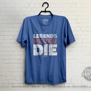 May include: A blue t-shirt with the text "Legends Never Die" in white with red accents. The text has a distressed look.