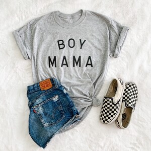 Peut inclure: Un t-shirt gris avec l'inscription "BOY MAMA" en noir, associ&eacute; &agrave; un short en jean et des chaussures &agrave; enfiler &agrave; carreaux noirs et blancs. Le short a une &eacute;tiquette Levi's.