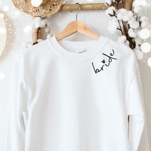 May include: A handmade wooden sign with the word "Welcome" in a whimsical font. It has a distressed white background and a dark brown border, suitable for a front door or hallway.