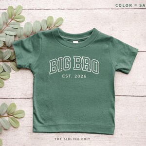 Puede incluir: Camiseta verde salvia para ni&ntilde;os peque&ntilde;os con el texto "BIG BRO EST. 2026" en blanco, con letras de estilo universitario. La camiseta tiene mangas cortas y cuello redondo. Las palabras "COLOR = SAGE" est&aacute;n en la parte superior y "THE SIBLING EDIT" en la parte inferior.