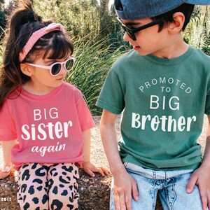 Puede incluir: Dos ni&ntilde;os con gafas de sol y camisetas a juego. La camiseta de la ni&ntilde;a es rosa y dice "BIG Sister again" en blanco. La camiseta del ni&ntilde;o es verde y dice "Promoted to BIG Brother" en blanco.