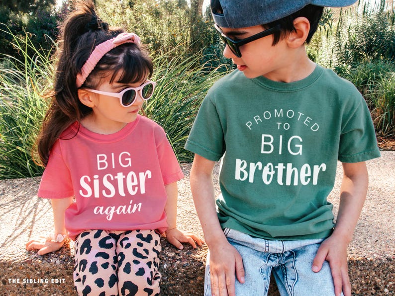 Puede incluir: Dos ni&ntilde;os con gafas de sol y camisetas a juego. La camiseta de la ni&ntilde;a es rosa y dice "BIG Sister again" en blanco. La camiseta del ni&ntilde;o es verde y dice "Promoted to BIG Brother" en blanco.