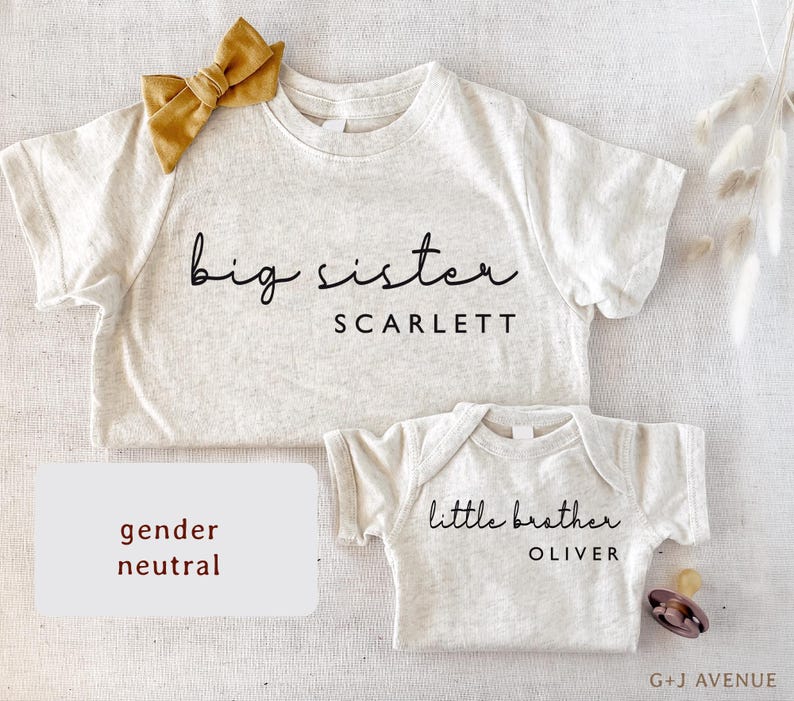 May include: Two light gray baby shirts, one with "big sister SCARLETT" and a mustard bow, the other with "little brother OLIVER". A pacifier is next to the smaller shirt. The words "gender neutral" are in a white box.