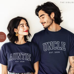 Puede incluir: Camisetas azul marino con letras blancas. Una camiseta dice "AUNTIE EST. 2026" y la otra "UNCLE EST. 2026". Un hombre y una mujer llevan las camisetas. Tambi&eacute;n se ven las palabras "more colors" y "THE SIBLING EDIT".