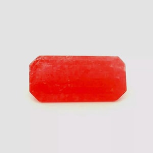 May include: A bright red, faceted, rectangular gemstone with a rough, textured surface.