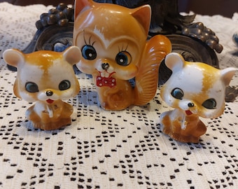 May include: Three ceramic figurines of animals with large eyes. A brown squirrel with a red bow tie, a brown and white mouse, and a white and brown mouse.