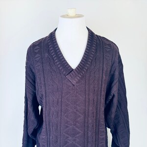 May include: A dark purple v-neck sweater with a cable knit pattern.