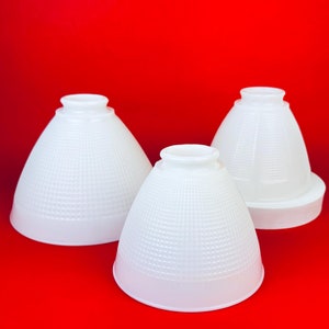 May include: Three white lampshades with a textured surface. The lampshades are cone-shaped and have a white, textured surface.