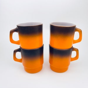May include: Set of four ombre ceramic mugs with a brown to orange gradient. The mugs are stacked in pairs.